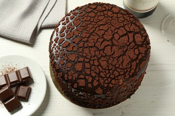Delicious truffle cake and chocolate pieces on light wooden table, above view
