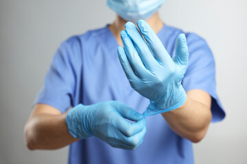 Doctor wearing light blue medical gloves on grey background, closeup