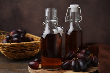 Bottles with wine vinegar and grapes on wooden table, closeup