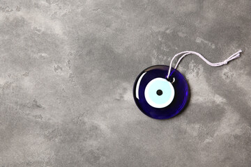 Evil eye amulet on grey table, top view. Space for text