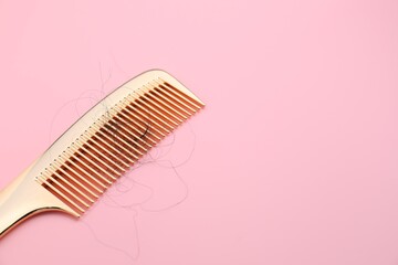 Comb with lost hair on pink background, space for text