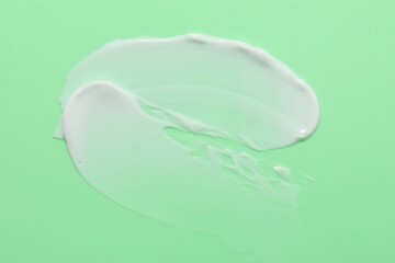Samples of face cream on green background, top view