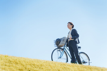 Obraz premium 青空と自転車通勤するビジネスマン