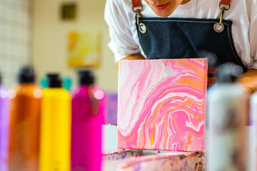 Group of Asian generation z people learning acrylic pouring art on canvas workshop at art studio....