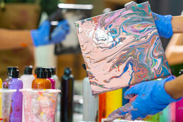 Group of Asian generation z people learning acrylic pouring art on canvas workshop at art studio. Young artist university student enjoy and fun creating colorful abstract modern art painting in class.