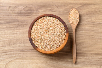 Brown quinoa seed in bowl with spoon on wooden background, Healthy food ingredient, Table top view