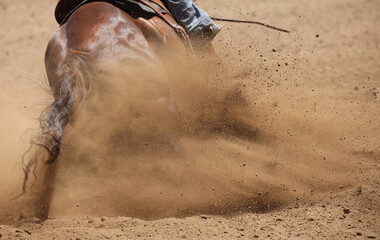 A racing horse showing the hip and a riders foot with mainly dirt flying everywhere.  Plenty of room for text.