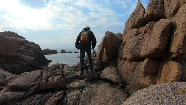 Un p&ecirc;cheur qui marche dans les rochers sur la c&ocirc;te de granit rose en Bretagne - France - 4K
