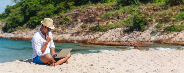 Banner Man traveler use laptop on summer beach blue sky. Asian man travel relax sitting summer beach island. Man typing laptop computer holiday business trip freelance working online with copy space