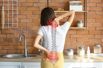 Young woman feeling back pain in kitchen