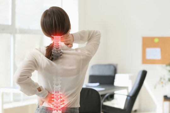 Young businesswoman suffering from back pain in office