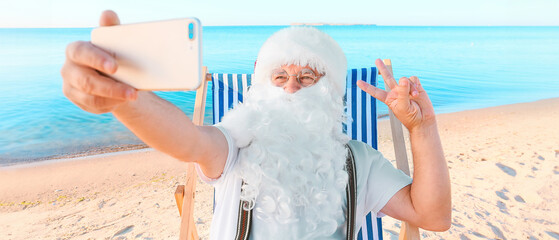 Santa Claus taking selfie at sea resort. Christmas vacation