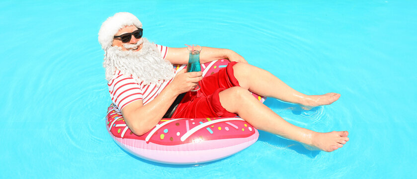Santa Claus relaxing on inflatable ring in swimming pool