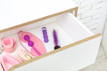 Open drawer with sex toys in room, closeup