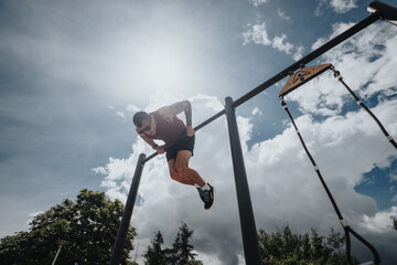 Focused athlete training on exercise equipment in an urban park, showcasing strength and fitness on...