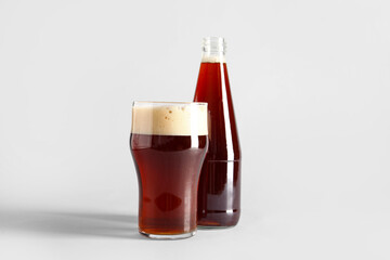 Glass and bottle of tasty kvass on grey background