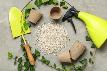 Composition with gardening tools, plants and granular fertilizer on grey grunge background
