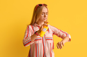 Young woman with mosquito repellent on yellow background