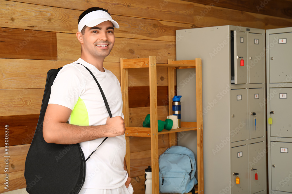 Sticker Male tennis player with racket case near locker in changing room