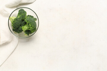Glass bowl with fresh broccoli cabbages on white background