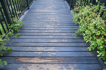 A scenic piece of nature with a rustic wooden bridge walkway surrounded by lush greenery in a park