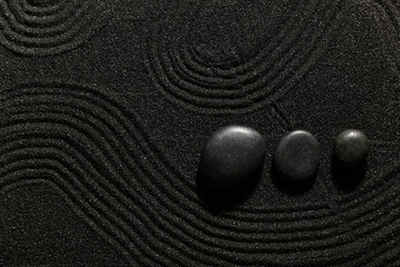 Stones on dark sand with lines in Japanese rock garden. Zen concept