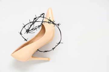 High-heeled shoe with plasters and barbed wire on white background. Uncomfortable shoes concept