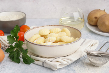 Bowl with tasty gnocchi, tomatoes and parsley on light background, closeup