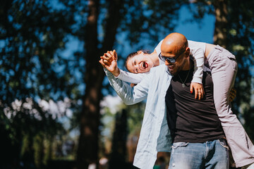 A joyful couple engages in playful activities under the bright sun in a lush park, sharing laughter and affection in a candid moment.