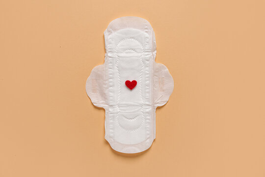 Menstrual pad with red heart on beige background