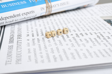 Obraz premium Newspapers and word NEWS made of cubes, closeup