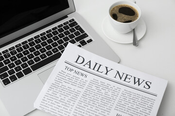 Daily newspaper with laptop and cup of coffee on white background