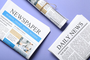 Different newspapers on lilac background