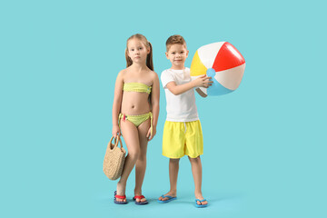 Cute little children with wicker bag and beach ball on blue background