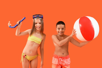 Cute little children in swimsuit with beach ball and snorkeling mask on orange background