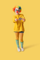 Funny little girl in disguise with paper fish on yellow background. April Fools' Day celebration