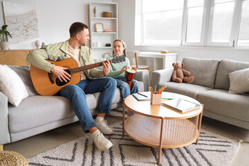 Father and his daughter playing music instruments at home