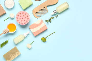 Hair scalp massagers with shampoo bars, different skincare products and flowers on blue background