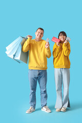 Obraz premium Young couple in love with shopping bags, wallet and money on blue background