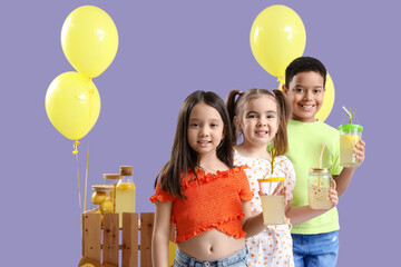 Cute little children with lemonade and stand on lilac background