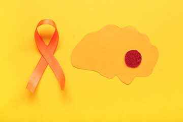 Paper brain and orange ribbon on yellow background. Multiple Sclerosis Awareness Month