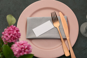 Beautiful table setting with blank invitation card and flowers on black background