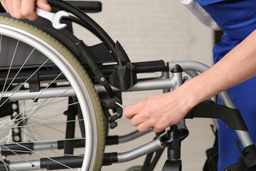 Male worker repairing wheelchair in room, closeup