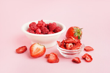 Bowls with freeze-dried strawberries and raspberries on pink background