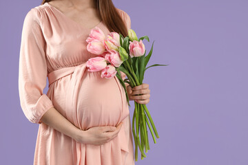 Young pregnant woman with tulips on lilac background, closeup