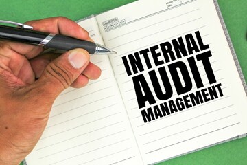 hand holding a pen and book with the words internal audit management