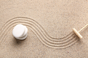 Spa stones and rake on sand with lines