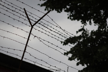 Shallow depth of field (selective focus) details with barbed wire on the outer wall of a prison in...