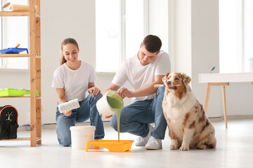 Happy young couple with paint and cute dog with brush planning painting walls in their new house