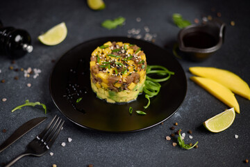 Traditional tuna and mango tartare on black ceramic plate